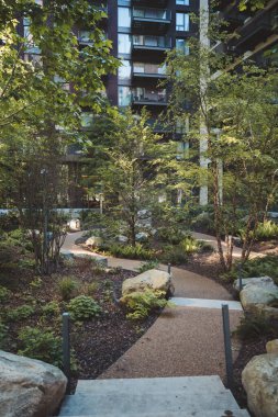 Vauxhall, Londra (124; İngiltere - 2021.06.13: Embassy Gardens 'da yeni inşa edilen lüks apartman dairelerinin yanındaki küçük park manzarası