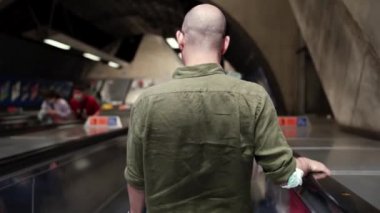 Sarhoş adam Londra Köprüsü Jübile Hattı metro istasyonunda yürüyen merdivende duruyor.