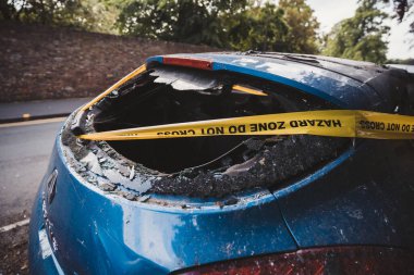 Londra - İngiltere - 2021.06.12: Yana park edilmiş, terk edilmiş, çalıntı mavi bir araba, sarı ile bağlanmış, çizgili değil.