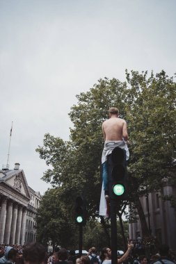 Londra (124; İngiltere - 2021.07.12: Genç İngiliz futbol taraftarı Trafalgar Meydanı 'ndaki trafik ışığının tepesinde gömleksiz oturuyor