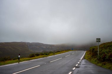 Kardan Donya, Galler 2025.09.21 Islak bir dağ yolu kalın sis ve engebeli tepelerin üzerinde alçak bulutlar arasında kaybolur Galler dağlarının kasvetli güzelliğini yakalar.. 
