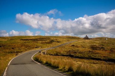 Kardan Donya, Galler 2025.09.20 Çimenli yamaçların ve engebeli kaya oluşumlarının üzerinde yükselen güneşli bir tepe Eryri Ulusal Parkı 'nın açık mavi gökyüzü altında. 