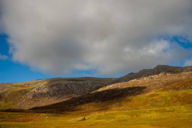Snowdonia, Galler 2025.09.21 Engebeli tepeler üzerinde dramatik ışık ve gölgeler gri bulutlar altında kayalık dokular ve mavi gökyüzü. 