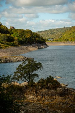 Kardan Donya, Galler 2025.09.20 Çimenli yamaçların ve engebeli kaya oluşumlarının üzerinde yükselen güneşli bir tepe Eryri Ulusal Parkı 'nın açık mavi gökyüzü altında. 