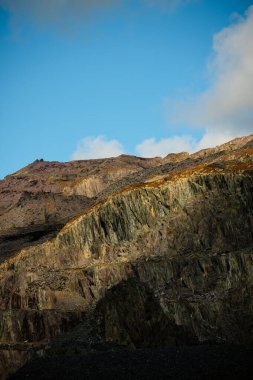 Snowdonia, Galler 2025.09.20 dik taş ocağı kayalıkları Eryri Ulusal Parkı 'ndaki parlak mavi gökyüzüne karşı öğleden sonra güneşiyle aydınlandı.. 