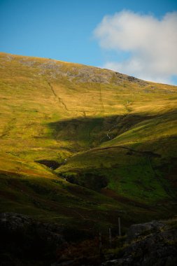 Kardan Donya, Galler 2025.09.21 Sıcak güneş ışığı yeşil ve altın vadi yamaçlarına yumuşak gölgeler saçar açık mavi gökyüzünün altında kıvrımlı bir dere vardır.. 