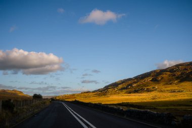 Snowdonia, Galler 2025.09.21 Altın güneşli tepelerden ve engebeli dağ yamaçlarından geçen boş bir yol.. 