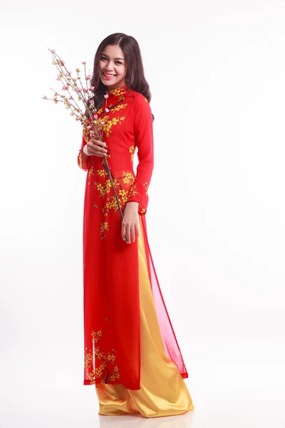 Krásná vietnamská žena s červeným ao dai drží třešňový květ pro oslavu Lunární Nový rok — Stock fotografie