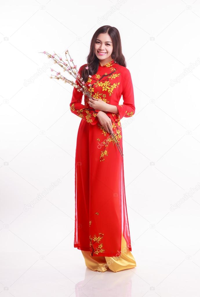 Beautiful Vietnamese woman with red ao dai holding cherry blossom for celebrate lunar new year