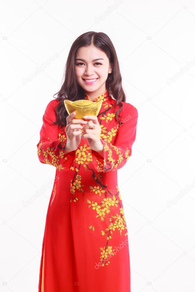 Beautiful Vietnamese woman with red ao dai holding lucky new year ornament - stack of gold