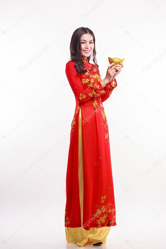 Beautiful Vietnamese woman with red ao dai holding lucky new year ornament - stack of gold