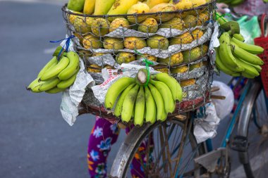 Typical street fruit vendor with palm-leaf conical hat moving at the street in road.