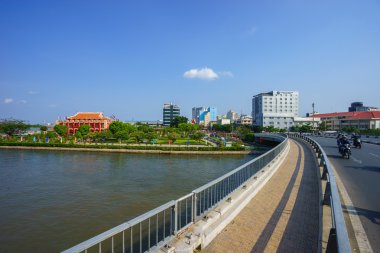 Landscape of Nha Rong port under blue sky on day, statue of Ho chi Minh before commemorative house, Vietnamese flag fly, pot of green tree, Viet Nam
