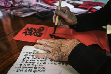 the old man with traditional black costume, white beard drawing calligraphy ancient distich in Long Son, Ba Ria Vung Tau,Vietnam to celebrating lunar new year coming. clipart