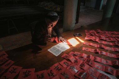 the old man with traditional black costume, white beard drawing calligraphy ancient distich in Long Son, Ba Ria Vung Tau,Vietnam to celebrating lunar new year coming. clipart