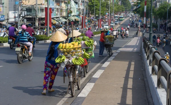 Vendedor típico de fruta callejera con sombrero cónico de hoja de palma que se mueve en la calle en la carretera . — Foto de Stock