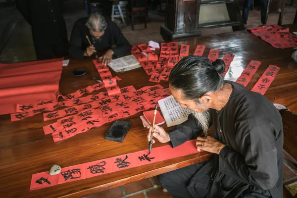 The old man with traditional black costume, white beard drawing calligraphy ancient distich in Long Son, Ba Ria Vung Tau,Vietnam to celebrating lunar new year coming. — Stock Photo, Image