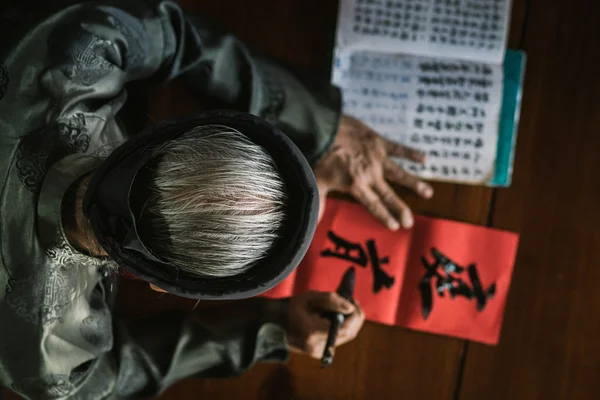 Il vecchio con costume tradizionale nero, barba bianca disegno calligrafia antico distich in Long Son, Ba Ria Vung Tau, Vietnam per celebrare il nuovo anno lunare in arrivo . — Foto Stock