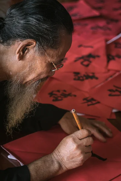 The old man with traditional black costume, white beard drawing calligraphy ancient distich in Long Son, Ba Ria Vung Tau,Vietnam to celebrating lunar new year coming. — Stock Photo, Image