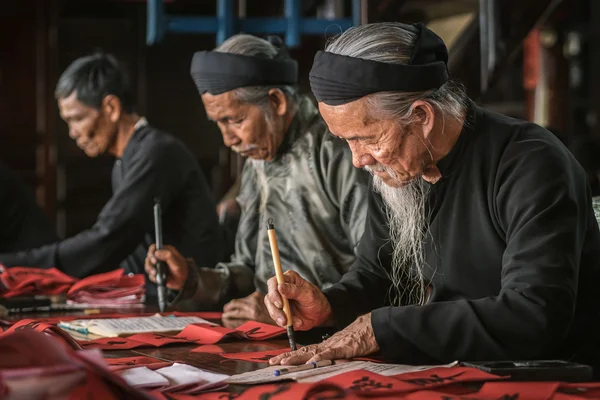 El anciano con traje negro tradicional, barba blanca dibujo caligrafía antigua distich en Long Son, Ba Ria Vung Tau, Vietnam a la celebración de año nuevo lunar que viene . Fotos de stock