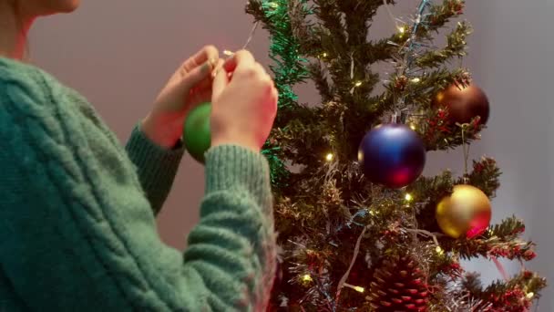 Mujer decoración de la mano del árbol de Navidad con bolas de colores. Año nuevo con luces de Navidad y abeto. — Vídeo de stock