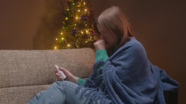 젊은 여성이 기침을 하고 약을 먹고 있어요. 크리스마스 저녁에 아픈 여자 격리 구역의 아파트에 혼자서. — 비디오