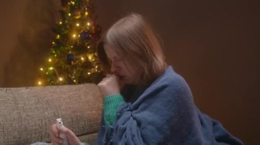 Öksüren ve ilaç alan genç bir kadın. Noel akşamı hasta bir kadın, karantinada tek başına..