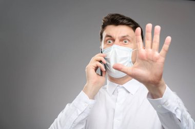 Yüz maskeli bir adam müşterisiyle telefonla konuşuyor, elinde durduğunu gösteren ifadeden korkuyor. Covid-19 test sonuçları pozitif..