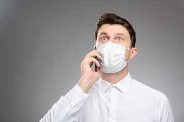 Yüz maskeli bir adam müşterisiyle telefonla konuşuyor, ifadeden korkuyor. Covid-19 test sonuçları pozitif..
