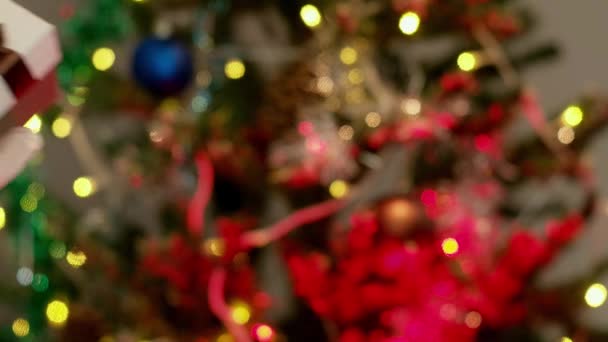Γυναίκα σε προστατευτικά γάντια δίνοντας χριστουγεννιάτικο δώρο σε έναν άνδρα με χριστουγεννιάτικο δέντρο στο παρασκήνιο. Πανδημία έννοια, προστατεύουν τους ανθρώπους που αγαπάτε. — Αρχείο Βίντεο