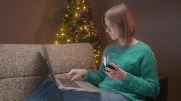 Nochebuena, mujer trabajando en un cuaderno, sola en casa con una copa de vino en cuarentena. — Vídeos de Stock