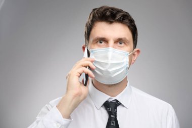 Yüz maskeli bir adam müşterisiyle telefonla konuşuyor. Koronavirüs salgınında koruyucu yüz maskesi takan bir ofis çalışanı.. 