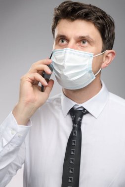 Yüz maskeli bir adam müşterisiyle telefonla konuşuyor. Koronavirüs salgınında koruyucu yüz maskesi takan bir ofis çalışanı.. 