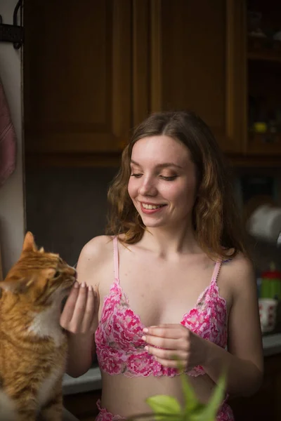 Mujer alimentando al gato en casa, feliz tiempo libre. El trabajo remoto desde el hogar le da mucho tiempo a las mascotas Imagen de stock