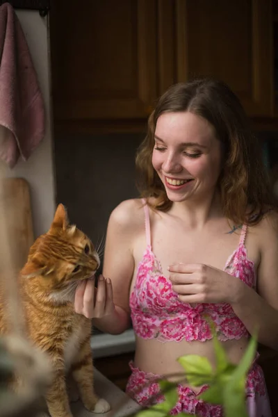 Mujer alimentando al gato en casa, feliz tiempo libre. El trabajo remoto desde el hogar le da mucho tiempo a las mascotas Imagen de stock