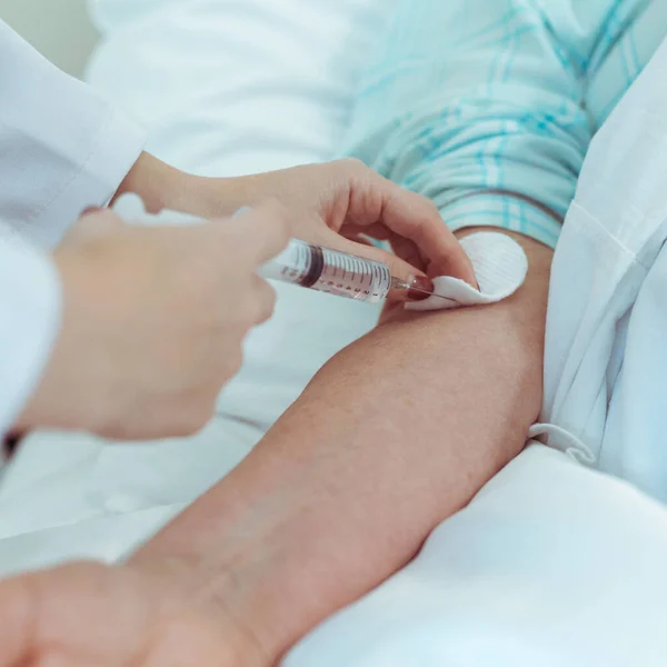 Seringa com uma injeção para mulher idosa na mão do médico. Vacinação contra o Coronavirus na Europa. — Fotografia de Stock