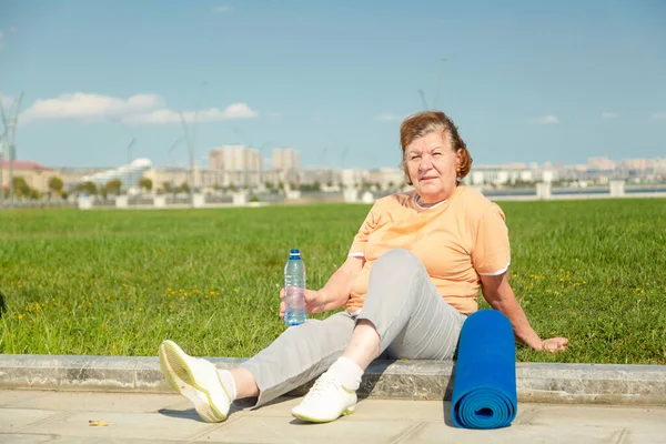 Pensionista mujer descansando después de la formación en el parque. — Foto de Stock