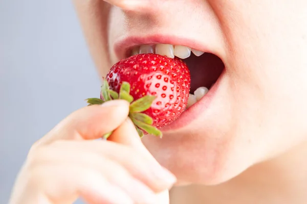 Primer plano de la boca de la mujer come una fresa madura, el concepto de un estilo de vida saludable con productos orgánicos y vitaminas. Imágenes de stock libres de derechos