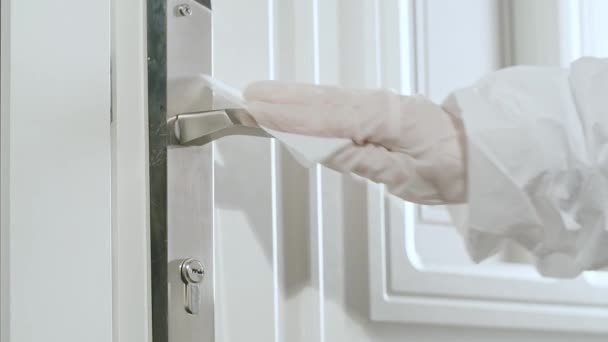 Mujer con guantes protectores extendiendo desinfectante en una manija de la puerta y limpie con una servilleta especial. — Vídeo de stock