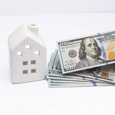 Banka kredisinin bir sembolü olarak, ellerinde nakit dolar banknotları olan beyaz bir ev..