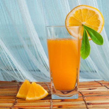 Taze sıkılmış portakal suyu dilimlenmiş portakal ve arka planda deniz olan yeşil yaprak..