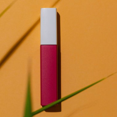 Turuncu arka planda ruj, yapraklı, yaz baskısı reklam amaçlı kozmetik ürünleri..