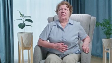 Yaşlı kadın karnını tutuyor, yemekten sonra kendini iyi hissetmiyor. Alerji ve mide hastalığı. Yüksek kalite fotoğraf