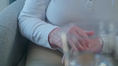 Yakın plan çekimde, bir adam yaşlı bir kadına bir bardak su veriyor, emeklilikten sonra destek oluyor. Torunum büyükanneme yardım ediyor ve istediğinde ona su veriyor.