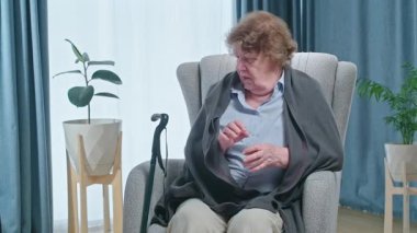 Titreyen yaşlı kadın koltuktan kalkıp yürümeye çalışıyor. Emeklilikten sonra sağlık sorunu var. Yüksek kalite 4k görüntü