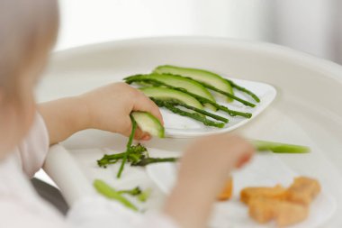 Bebek sebze yer, masaya pisler, kollarıyla yer ve sütten kesilir. Yüksek kalite fotoğraf