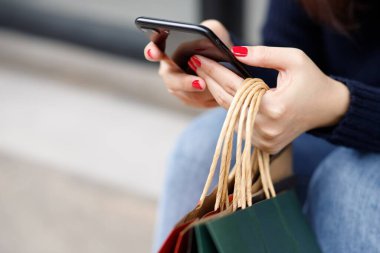 Alışveriş merkezinde alışveriş yapan kadınlar, telefon kullanıyor.