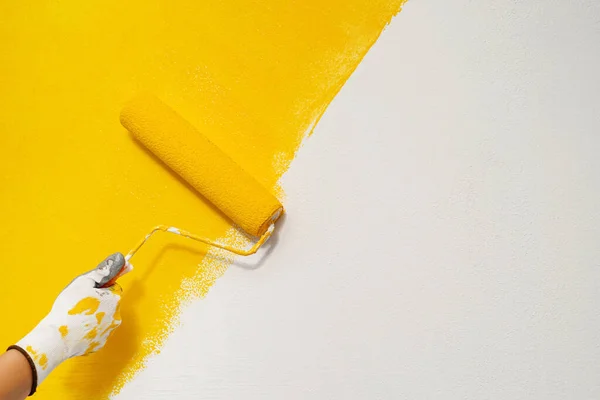 Ressam evin iç tarafıyla birlikte duvarları sarıya boyuyor..