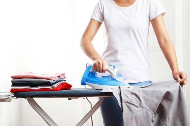 Kadın evde gömlek ütülüyor.