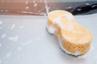 Sarı sünger ve sabun arabayı yıkamak için. Motor kaputu temizleniyor. Konsept araba yıkama. İleti yazmak için yer bırakın.